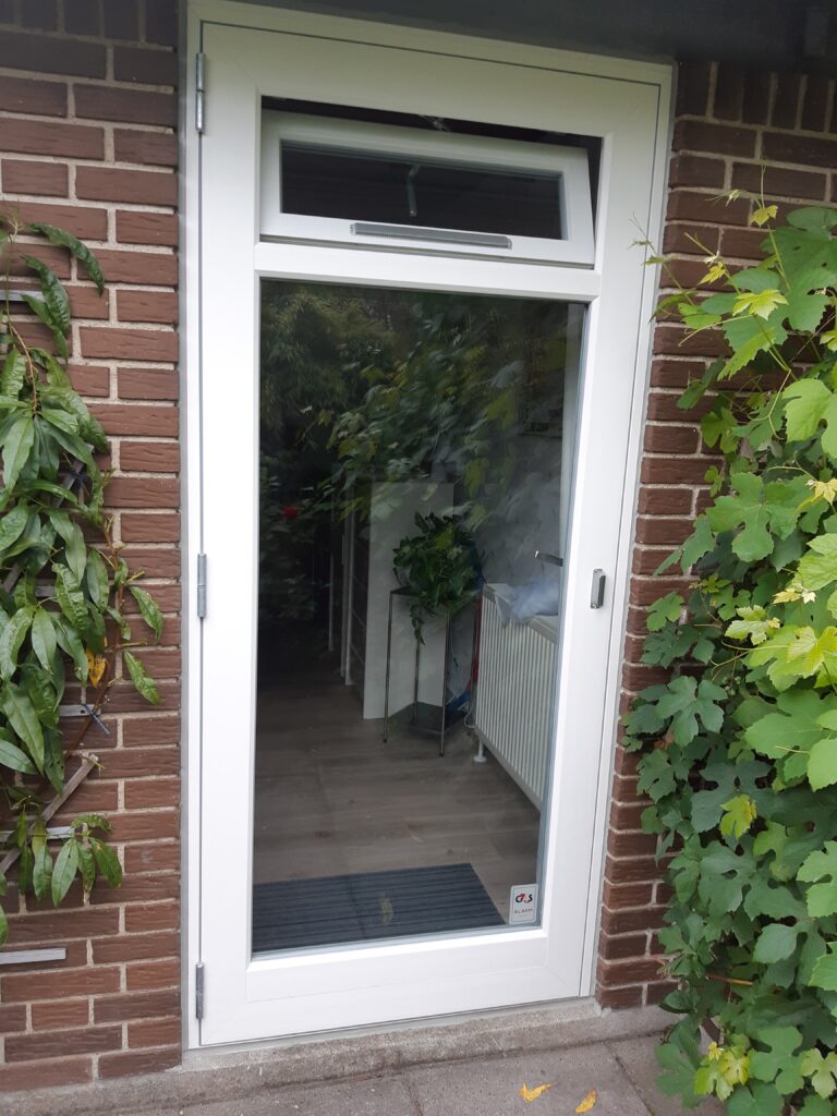 Hvid glasdør i murstensvæg med planter omkring