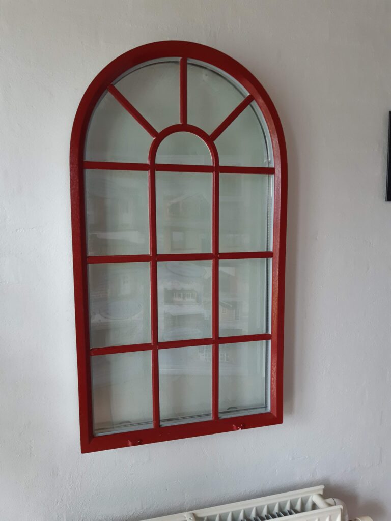 Buet vindue i plast med rød ramme på hvid væg