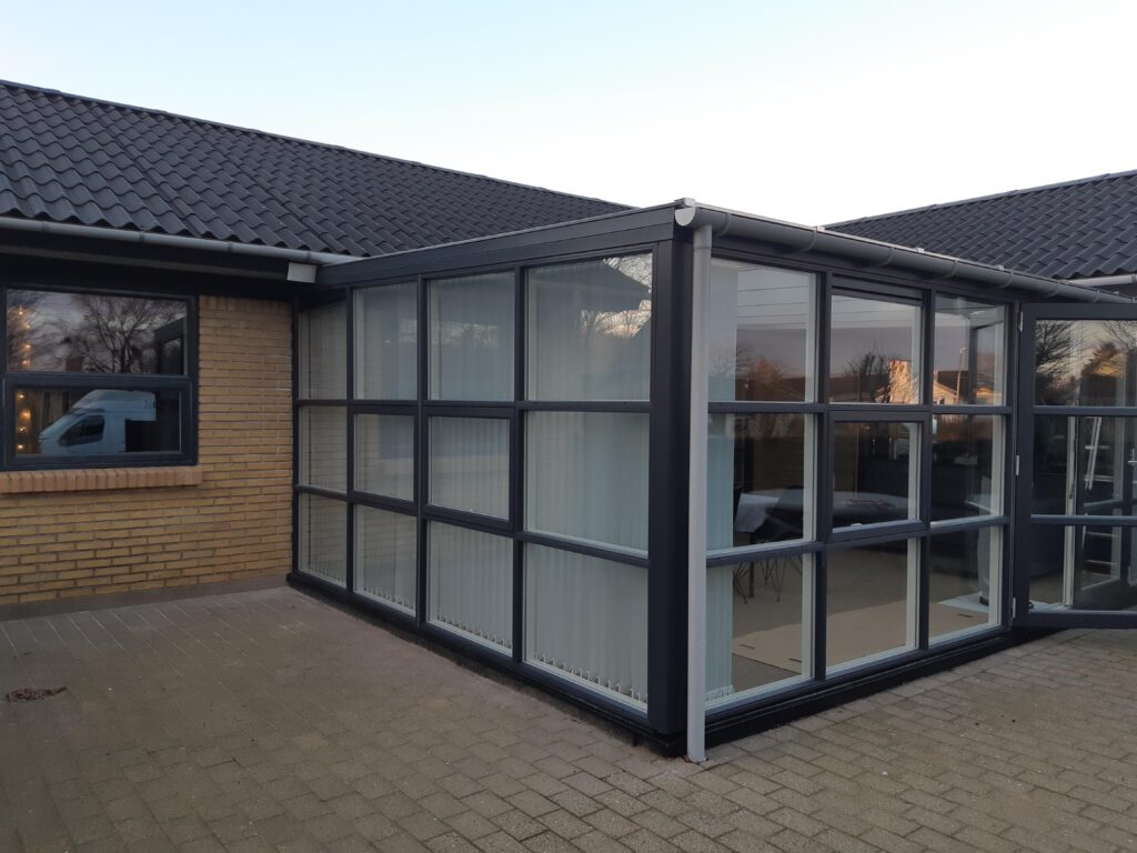 Moderne udestue med store glasvinduer og murstensvæg