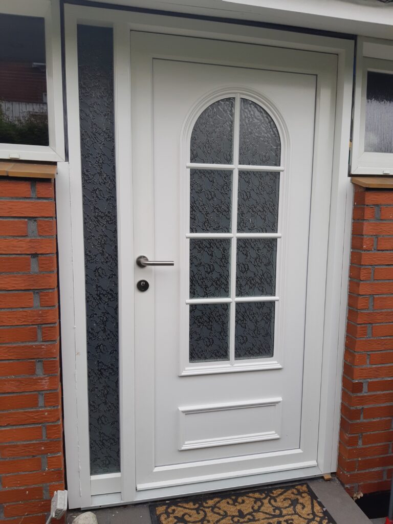 Hvid hoveddør i plast med glasruder og murstensvæg
