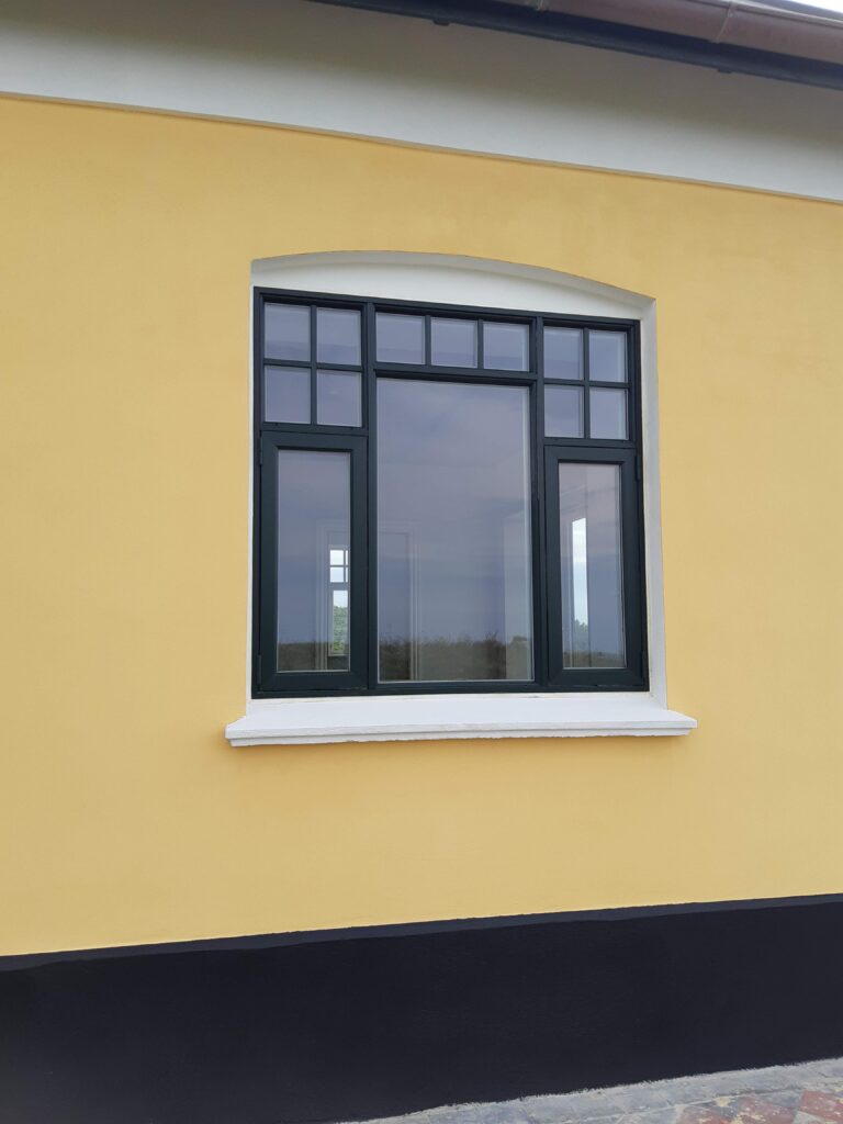 Sort vindue på gul husmur
