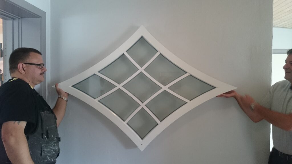 To mænd monterer diamantformet vindue på væg