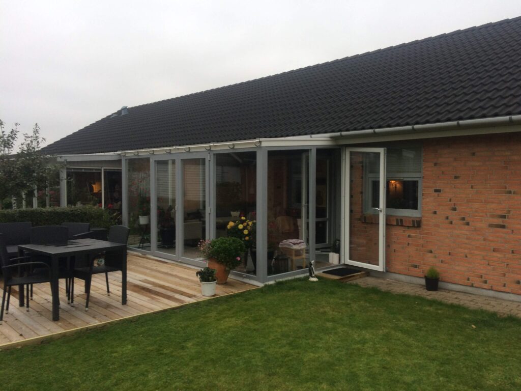 Murstenshus med terrasse og glasudestue